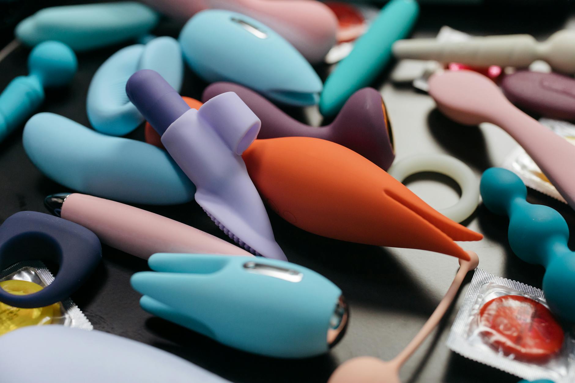 A hand holding a modern vibrator against a minimalistic purple backdrop