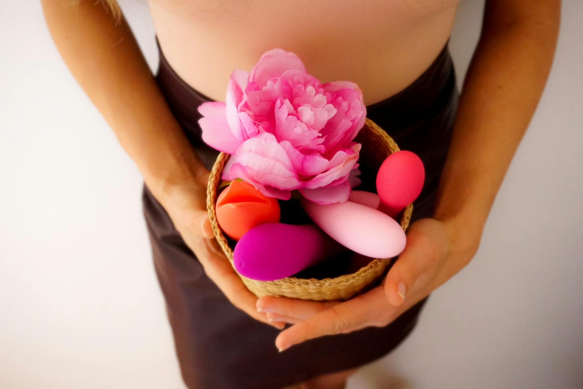 Basket of colorful vibrators and flowers representing openness to sexual exploration